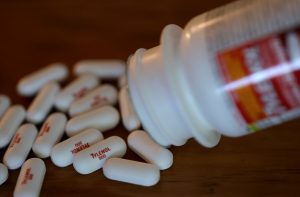 Imagem de um pote de Tylenol aberto e diversas pílulas na mesa