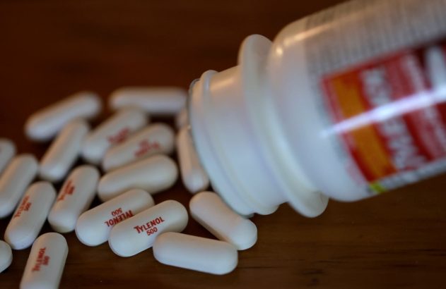 Imagem de um pote de Tylenol aberto e diversas pílulas na mesa