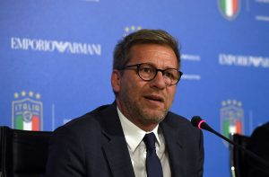 novo CEO da Armani, marca de luxo, está de terno preto, gravata preta e camisa branca, usa óculos e aparenta ter 60 anos