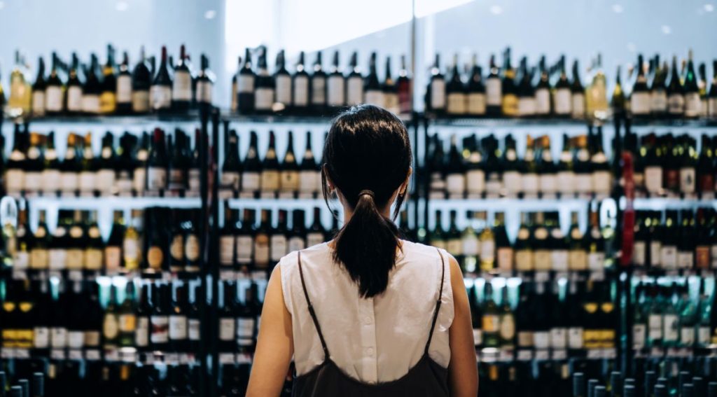 Uma mulher chinesa olha para uma vitrine de luxo com vinhos