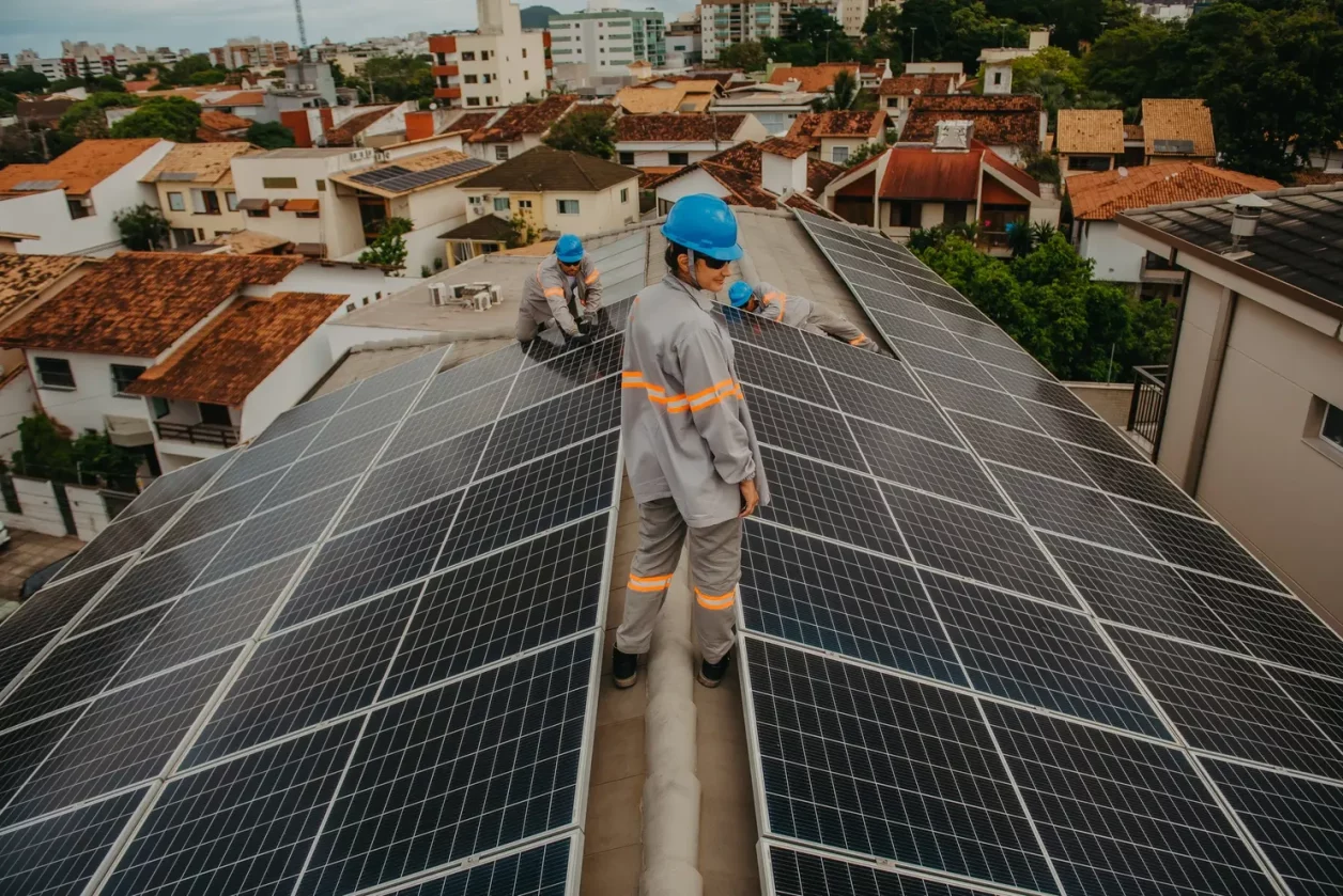a group of men standing on a roof with solar panels