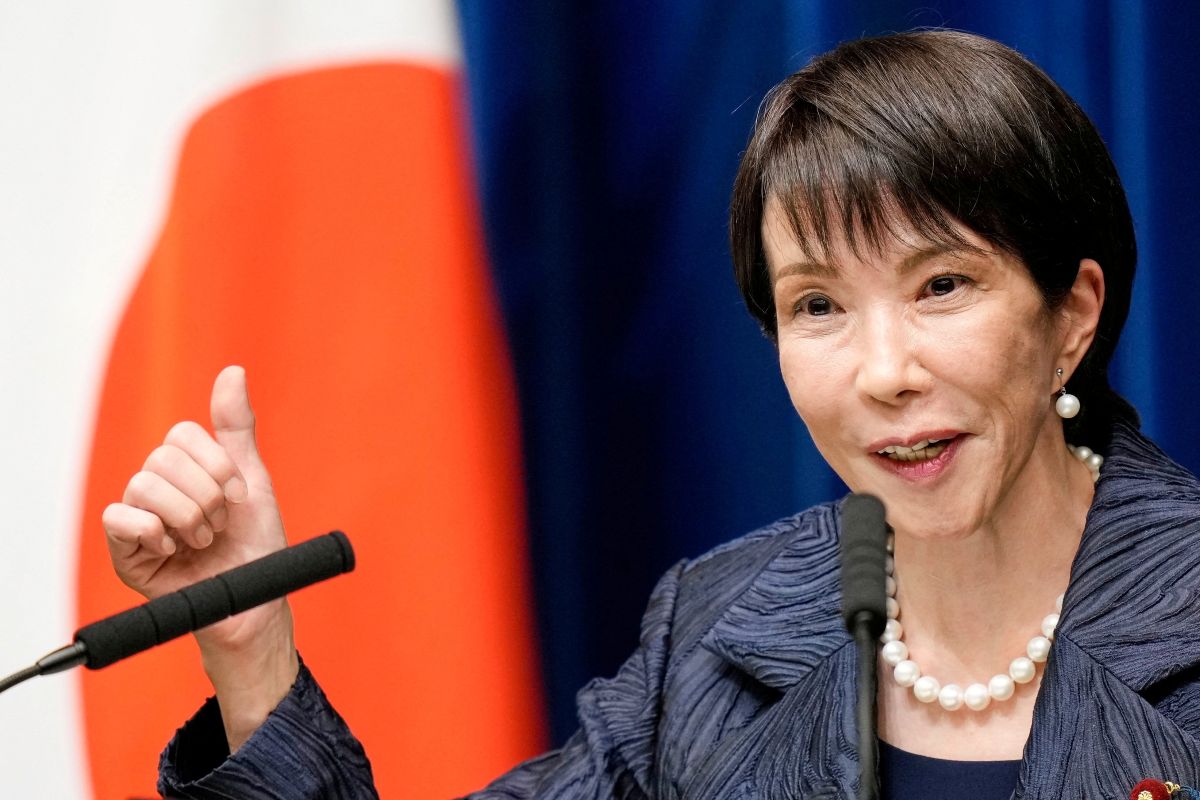 Nova premiê do Japão é uma mulher de cabelos escuros e curtos, está vestindo um blazer cinza e colar de pérolas