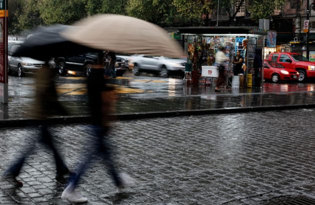 Foto da Cidade do México com pessoas de sombrinha, com chuva