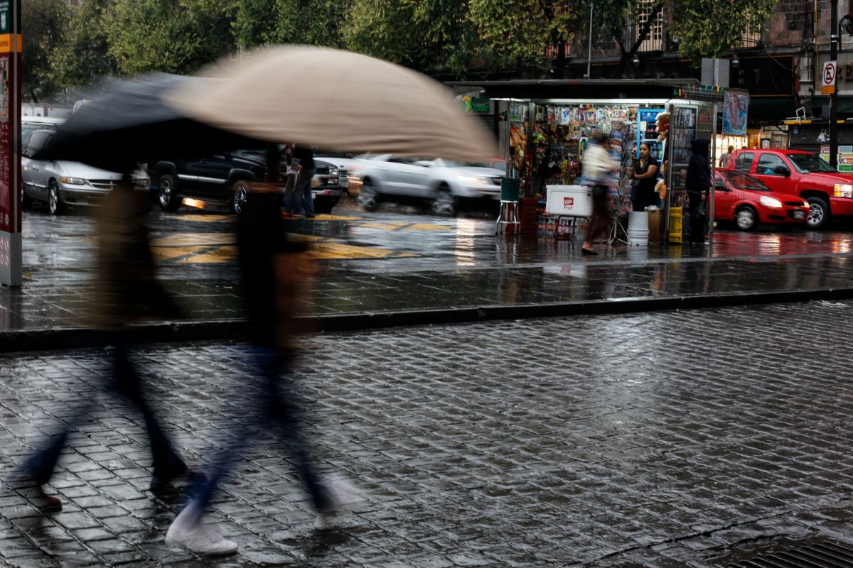 Foto da Cidade do México com pessoas de sombrinha, com chuva