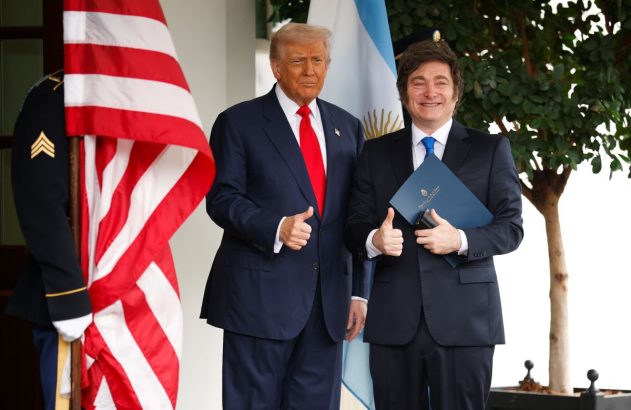 Donald Trump está de terno preto e gravata vermelha ao lado de Javier Milei, mais baixo, de terno preto e gravata escura