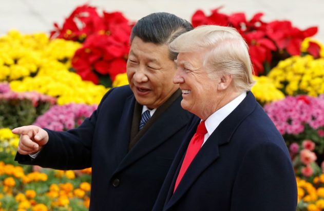 Os presidentes da China e dos EUA estão lado a lado em frente a flores coloridas