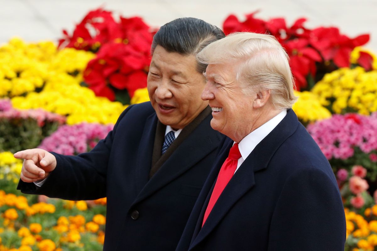 Os presidentes da China e dos EUA estão lado a lado em frente a flores coloridas
