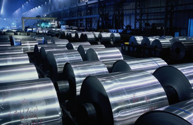 rolos de alumínio enfileirados dentro de uma fábrica