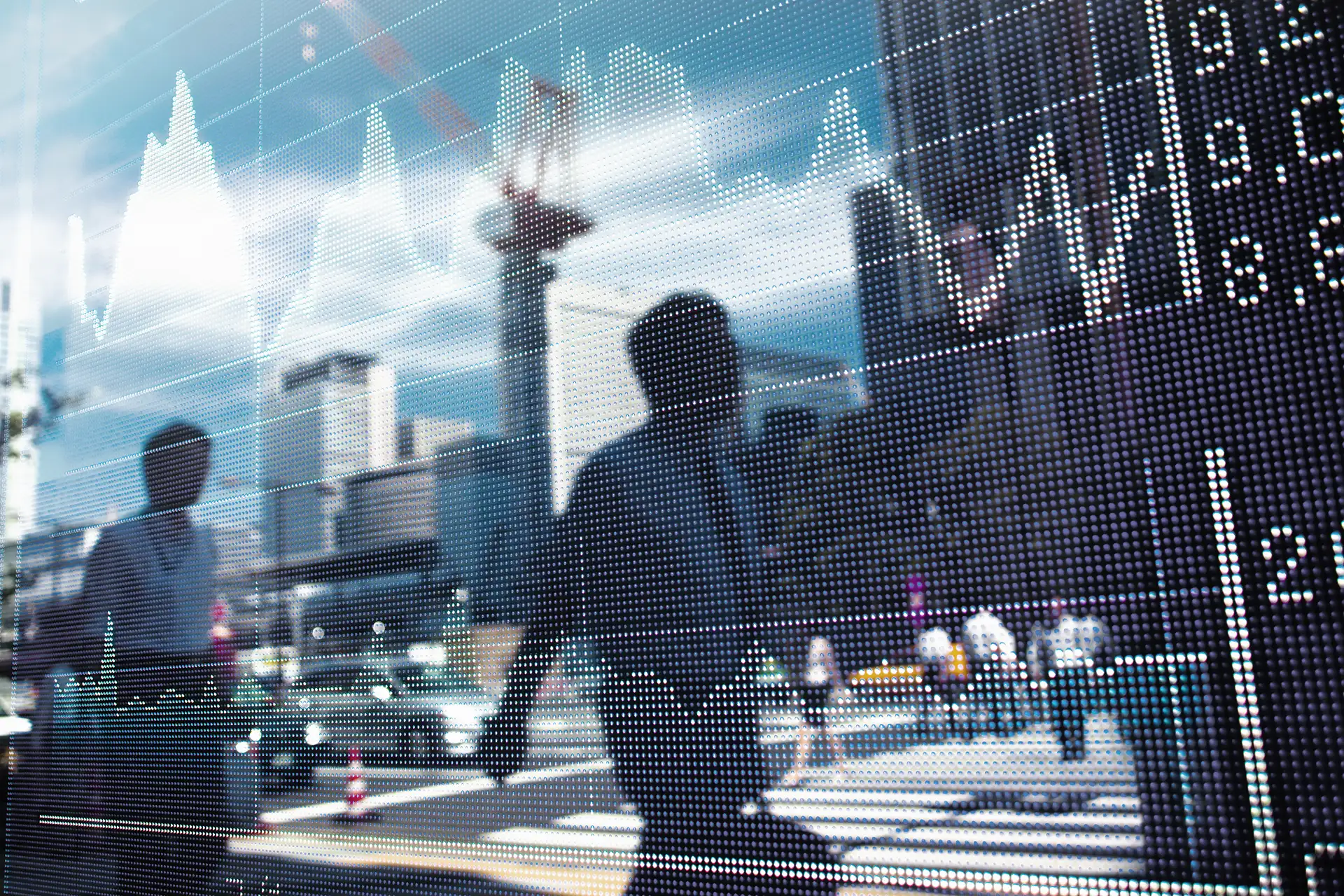 Reflexo de pessoas atravessando rua em frente a prédios, com gráfico financeiro exibido sobreposto no vidro.