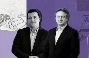 Duas figuras masculinas, com terno e camisa social, estão centralizadas em frente a um fundo roxo e cinza. No fundo, um desenho em estilo rascunho esboça os negócios do grupo: à esquerda, um pedaço de carne e toras de madeira (celulose); à direita, uma torre de refrigeração e um símbolo de radiação nuclear (energia nuclear). Os homens são os rmãos Joesley e Wesley Batista (JBS/J&F), com expressões sérias, olhando diretamente para frente.