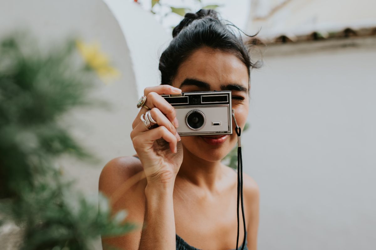 Moça usa uma câmera antiga para fazer fotos