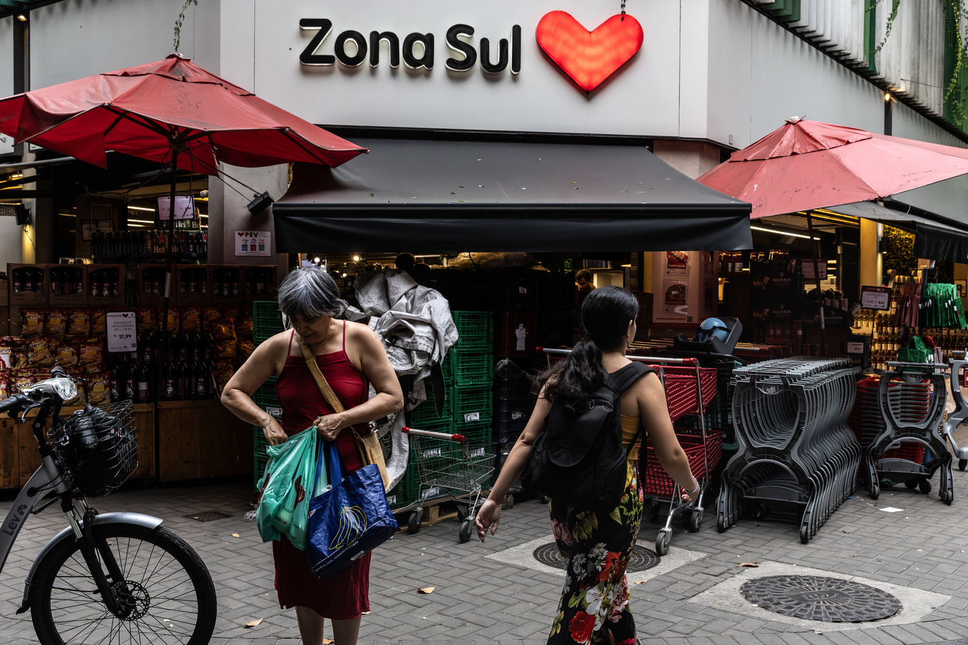 Uma consumidora carrega sacolas do lado de fora de um supermercado da rede Zona Sul, no Rio de Janeiro, Brasil