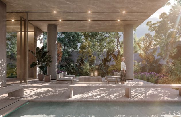 Área comum de edifício residencial com pé-direito alto, pilares de concreto e mobiliário contemporâneo. Uma mulher caminha pelo ambiente iluminado por luz natural.