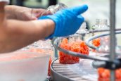 Funcionária farmacêutica em um controle de qualidade industrial verificando a produção de gomas nutricionais na fábrica